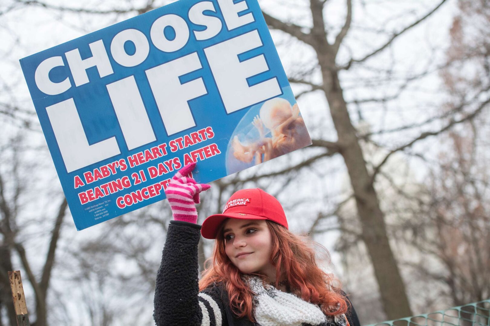 a person wearing a hat and holding a sign