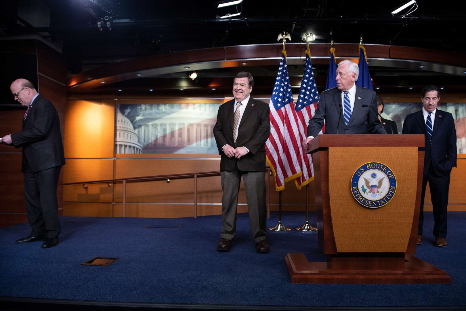 UNITED STATES - MARCH 9: Rep. Jim McGovern, D-Mass., left, checks his phone after it went off as House Majority Leader Steny Hoyer, D-Md., center, joined by Reps. Dutch Ruppersberger, D-Md., left, Karen Bass, D-Calif., chair of the Congressional Black Caucus, and Jamie Raskin, D-Md., speaks during a news conference calling for the removal of a bust from the Capitol of Chief Justice Roger Taney in Washington on Monday, March 9, 2020. (Photo by Caroline Brehman/CQ Roll Call)