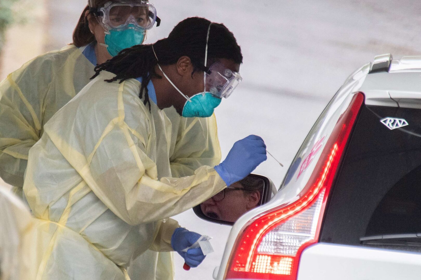 A health care professional applies a swab at a drive-thru coronavirus testing facility for residents who have an order from a provider on Quincy Street in Arlington, Va.