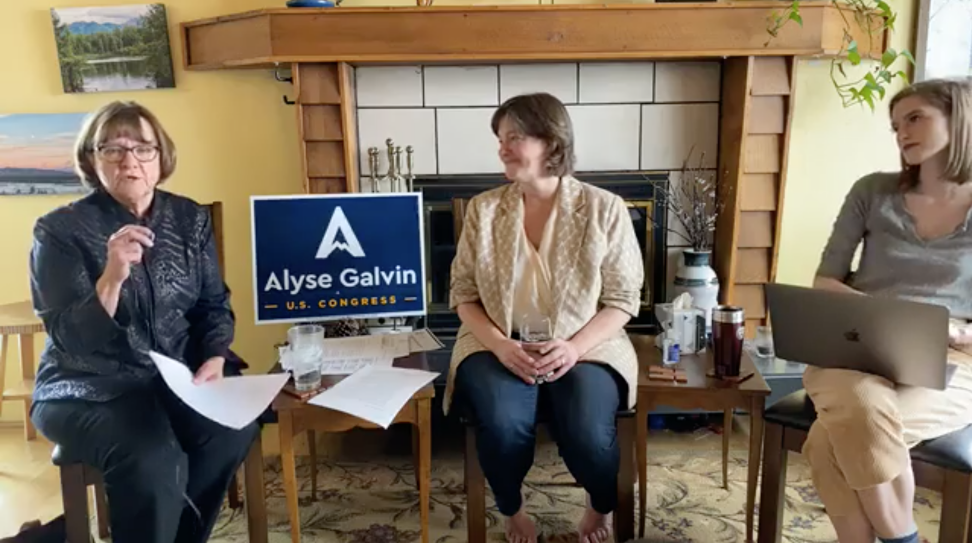 A barefoot Alyse Galvin, who is running for the House in Alaska, and commuications director Bridget Galvin listen as Shirley Pittz speaks on a Facebook Live video Wednesday about how parents can meet children's emotional and educational needs while schools are closed due to coronavirus.