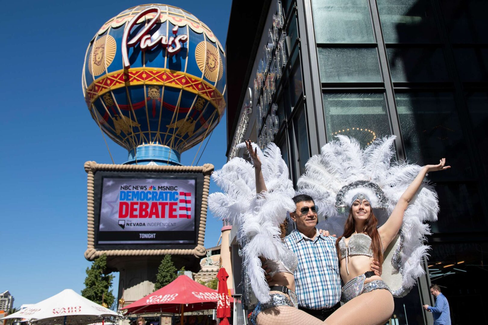 Showgirls pose with a tourist near the Paris Las Vegas hotel casino, site of a Democratic presidential debate, on Feb. 19, 2020. (Caroline Brehman/CQ Roll Call)