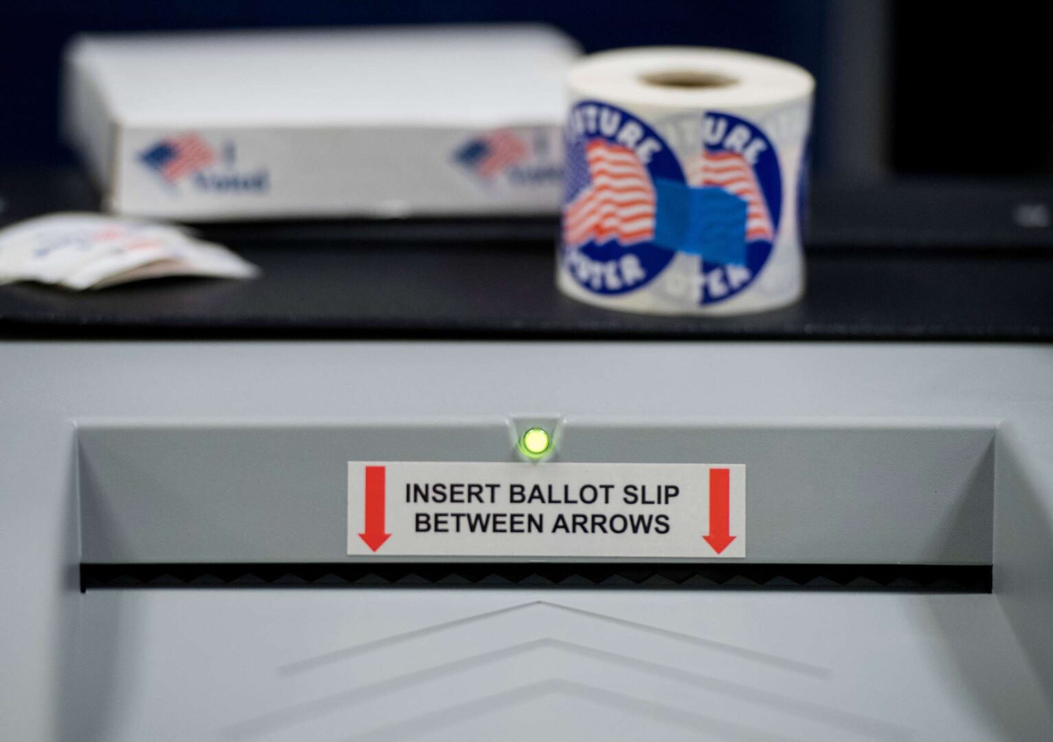 Voters insert their ballots into a machine.