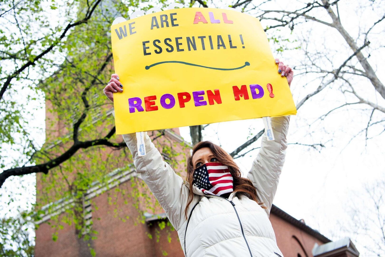 Natalie Brown, of Mt. Airy, Md., holds a sign in front of St. Anne's Episcopal Church in Annapolis, Md., during a demonstration to demand that GOP Gov. Larry Hogan lift restrictions that have closed businesses due to the spread of COVID-19.