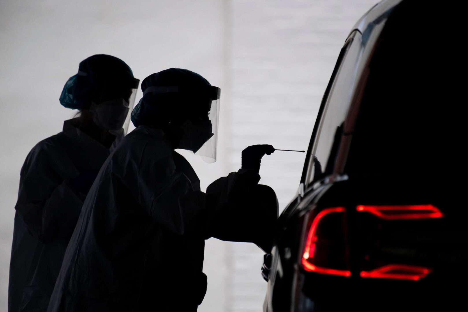 A healthcare worker conducts a COVID-19 test at a drive-thru testing facility at George Washington University on May 5, 2020.