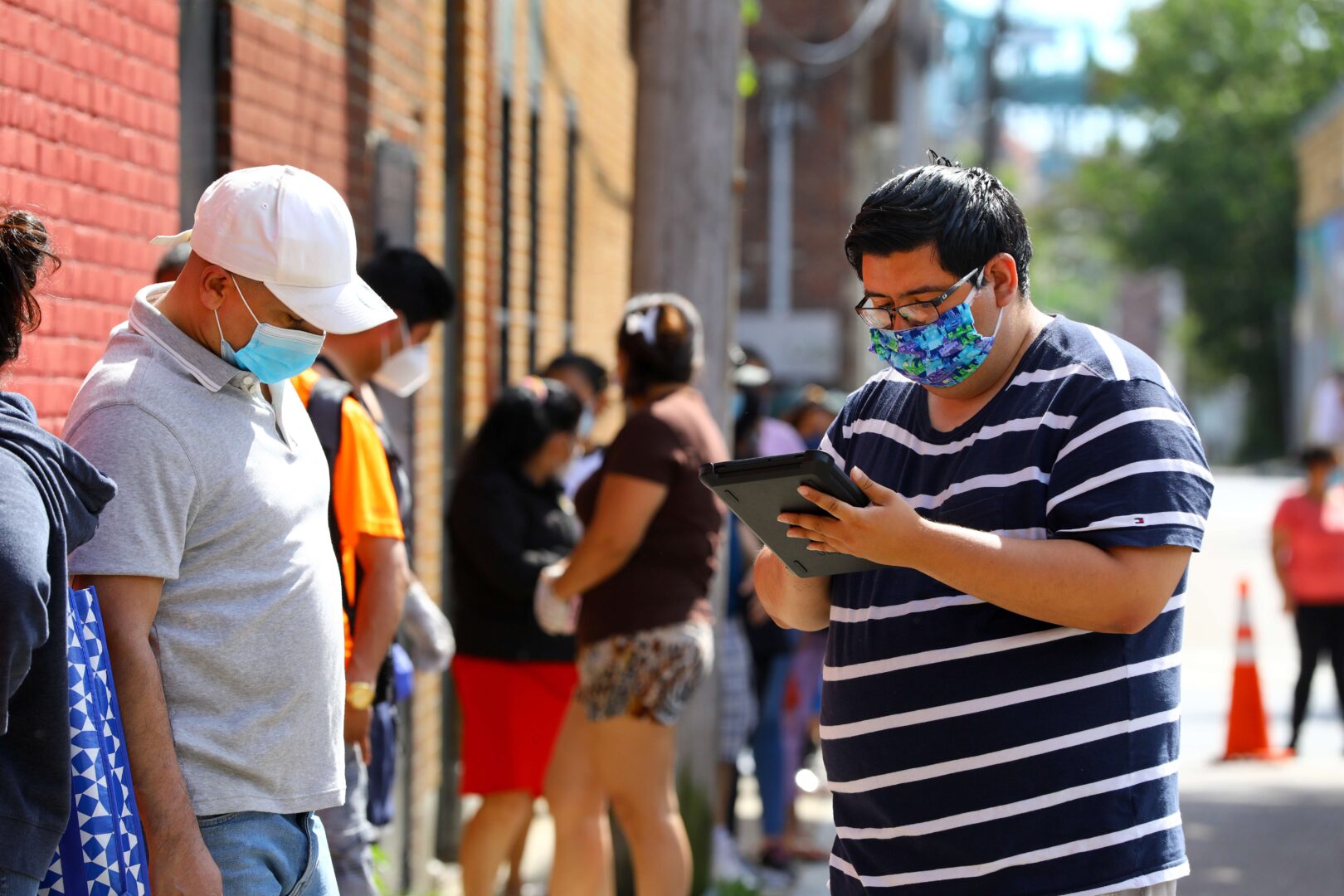 Census 2020 field organizer Jeffrey Tellez, right, interviews a resident in the food pantry line at the Chelsea Collaborative in Chelsea, Massachusetts, on June 4, 2020. 