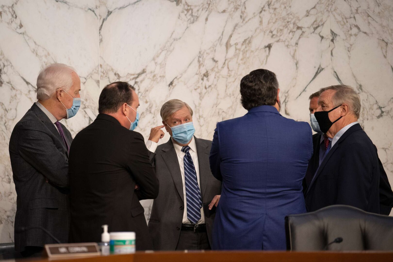 Chairman Lindsey Graham puts his finger near his ear on Wednesday as he confers with Sens. John Cornyn, Mike Lee, Ted Cruz, Richard Blumenthal and Richard J. Durbin during a break from the third day of Senate Judiciary confirmation hearings for Supreme Court nominee Amy Coney Barrett. 