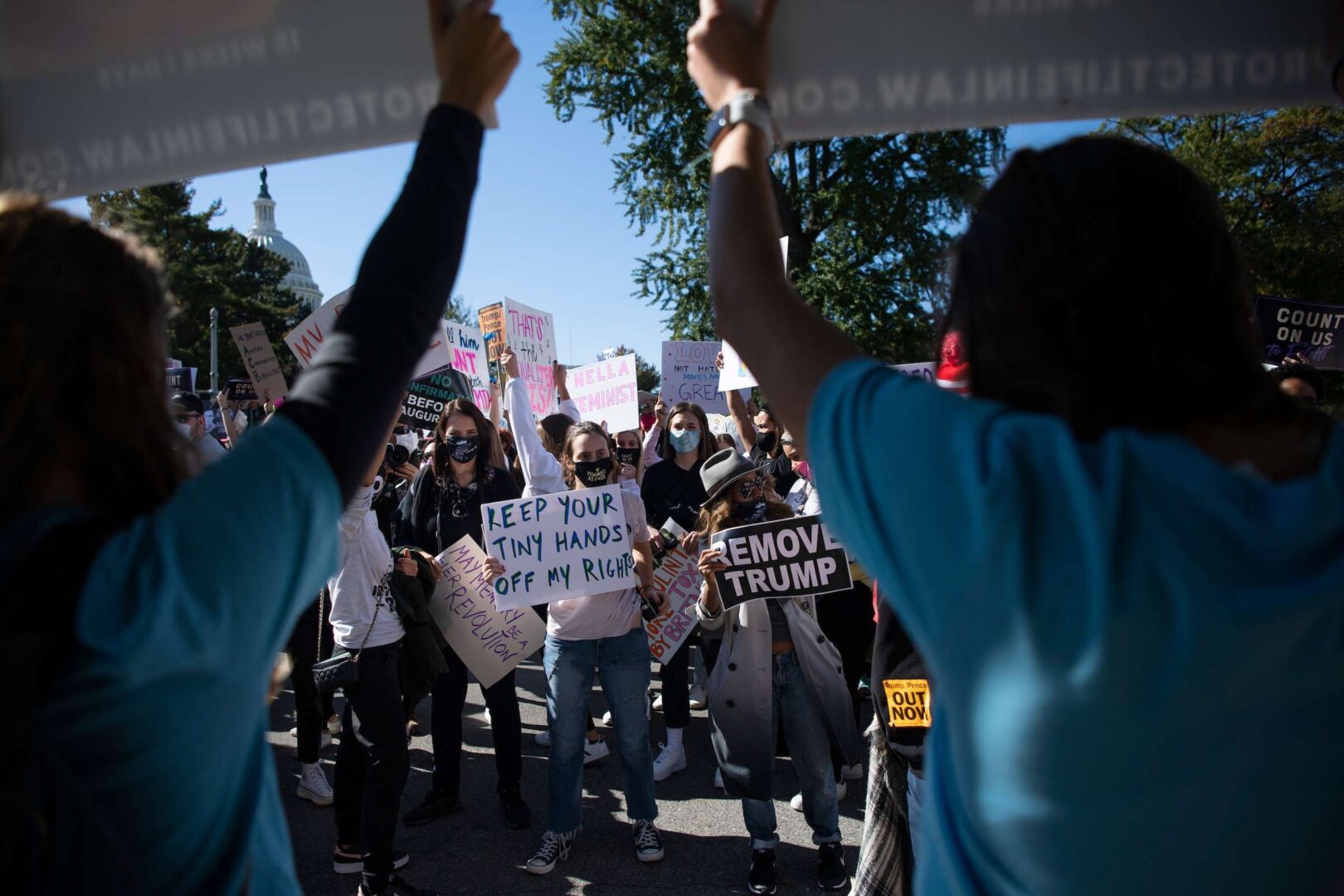 Participants in the Women’s March hold up signs Saturday outside the Supreme Court as they confront demonstrators in support of Amy Coney Barrett.