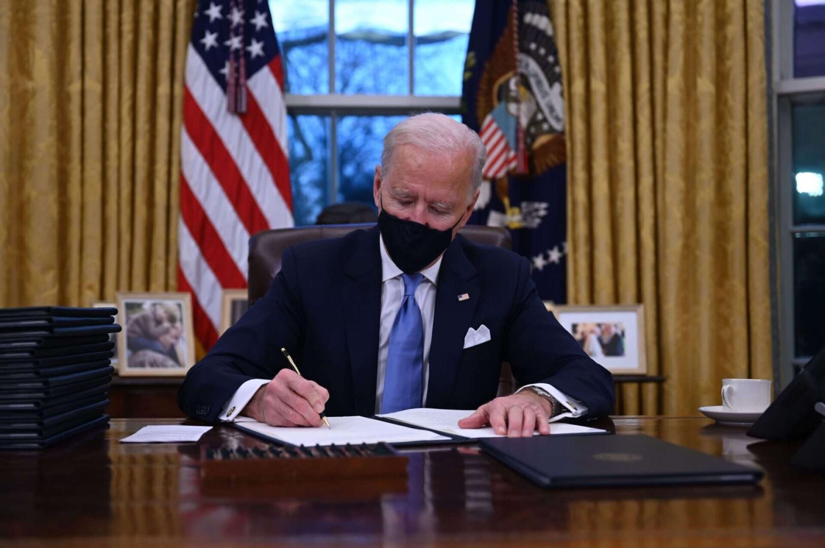 President Joe Biden sits in the Oval Office as he signs a series of orders at the White House after being sworn in on Jan. 20, 2021.