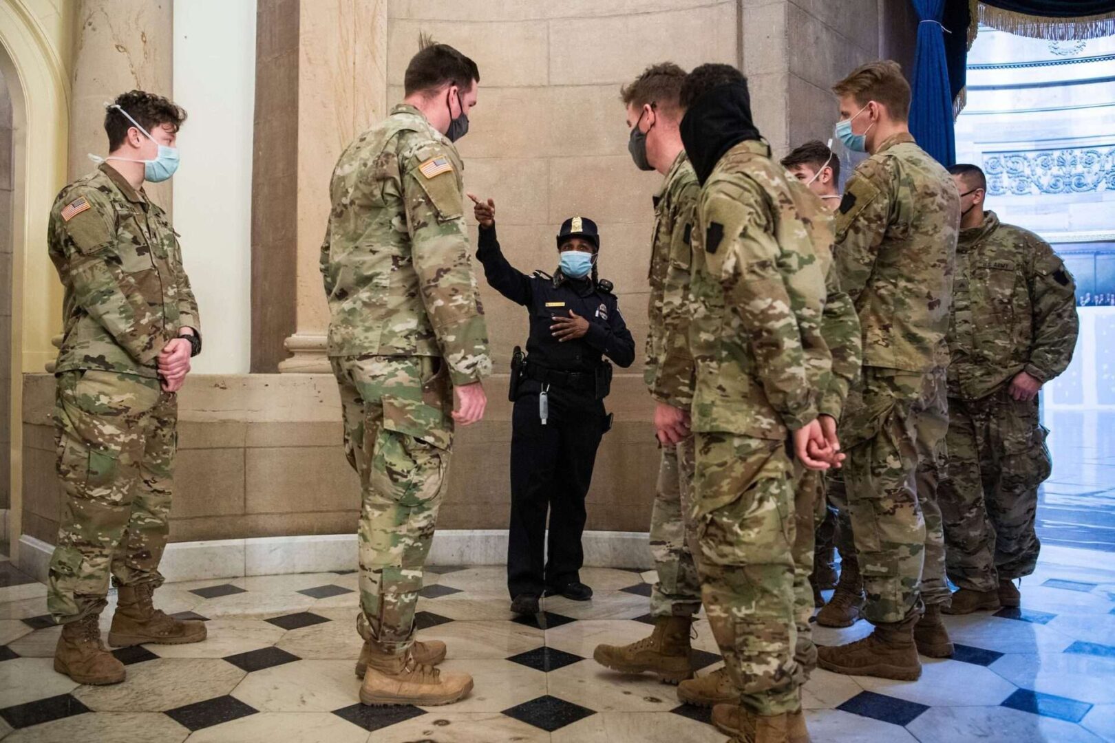 A Capitol Police officer talks with members of the Maryland National Guard outside the Capitol office of Speaker Nancy Pelosi, D-Calif., on Monday.