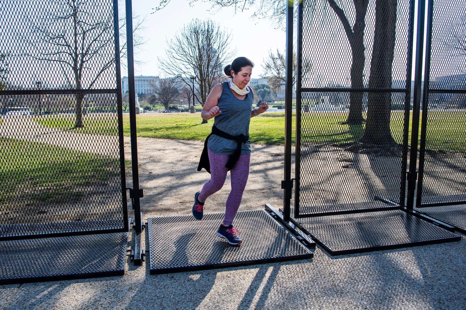 UNITED STATES - MARCH 22: A Capitol Hill resident runs through a portion of security fence along 3rd Street on Monday, March 22, 2021. Much of the outer fencing near the Capitol was removed over the weekend. (Photo By Tom Williams/CQ Roll Call)