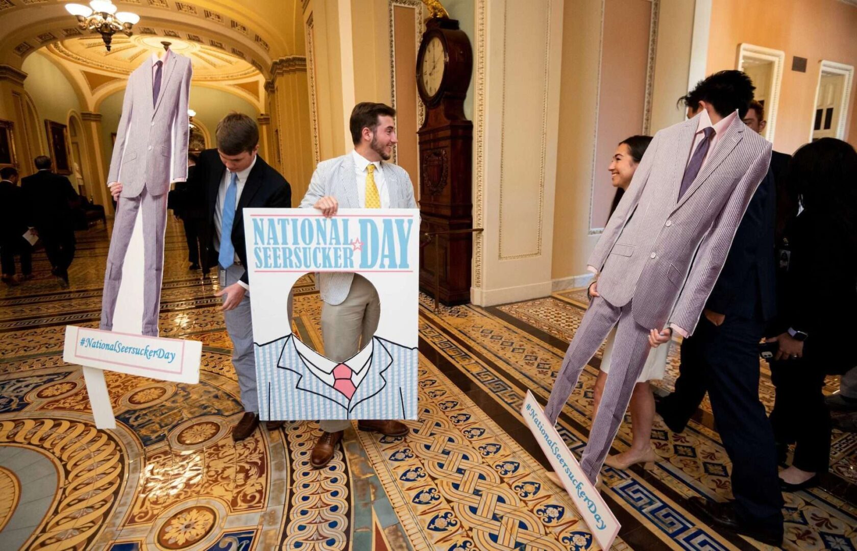 UNITED STATES - JUNE 17: Congressional staffers carry Nartional Seersucker Day cutout posters into the Ohio Clock Corridor for the annual Seersucker Thursday photo-op in the Capitol on Thursday, June 17, 2021. (Photo by Bill Clark/CQ Roll Call)
