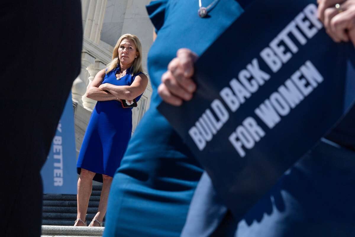 Rep. Marjorie Taylor Greene, R-Ga., passes by a Build Back Better for Women rally held by Democrats on the House steps on Friday.