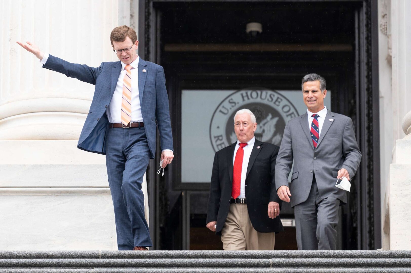From left, Rep. Dusty Johnson, R-S.D., checks how heavy the rain is falling as he along with Rep. Greg Pence, R-Ind., and Rep. Dan Meuser, R-Pa., walk down the House steps after the final vote of the week on Friday.