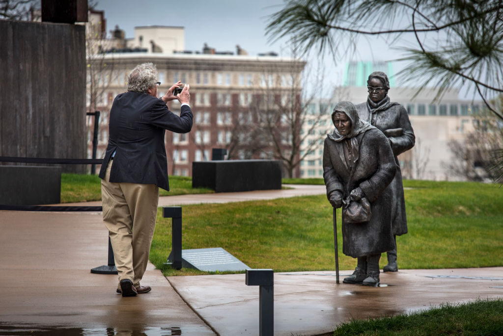 Our country’s leaders should be brave enough to confront uncomfortable history, Curtis writes. Above, a man takes a photo of Dana King's “Guided By Justice” statue, dedicated to Black women who sustained the Montgomery Bus Boycott, at the National Memorial for Peace and Justice in Montgomery, Ala. 