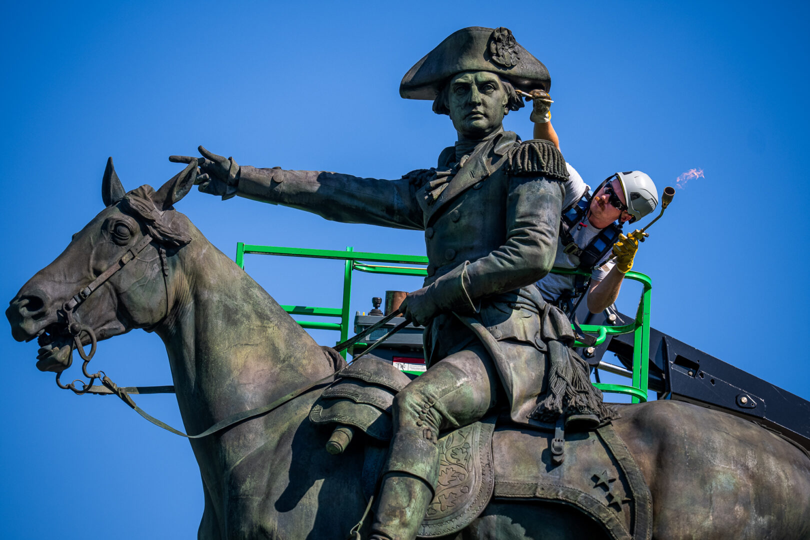 A worker applies hot wax on the statue of Gen. Nathanael Greene in Stanton Park on May 5 as part of a restoration process. (Tom Williams/CQ Roll Call)