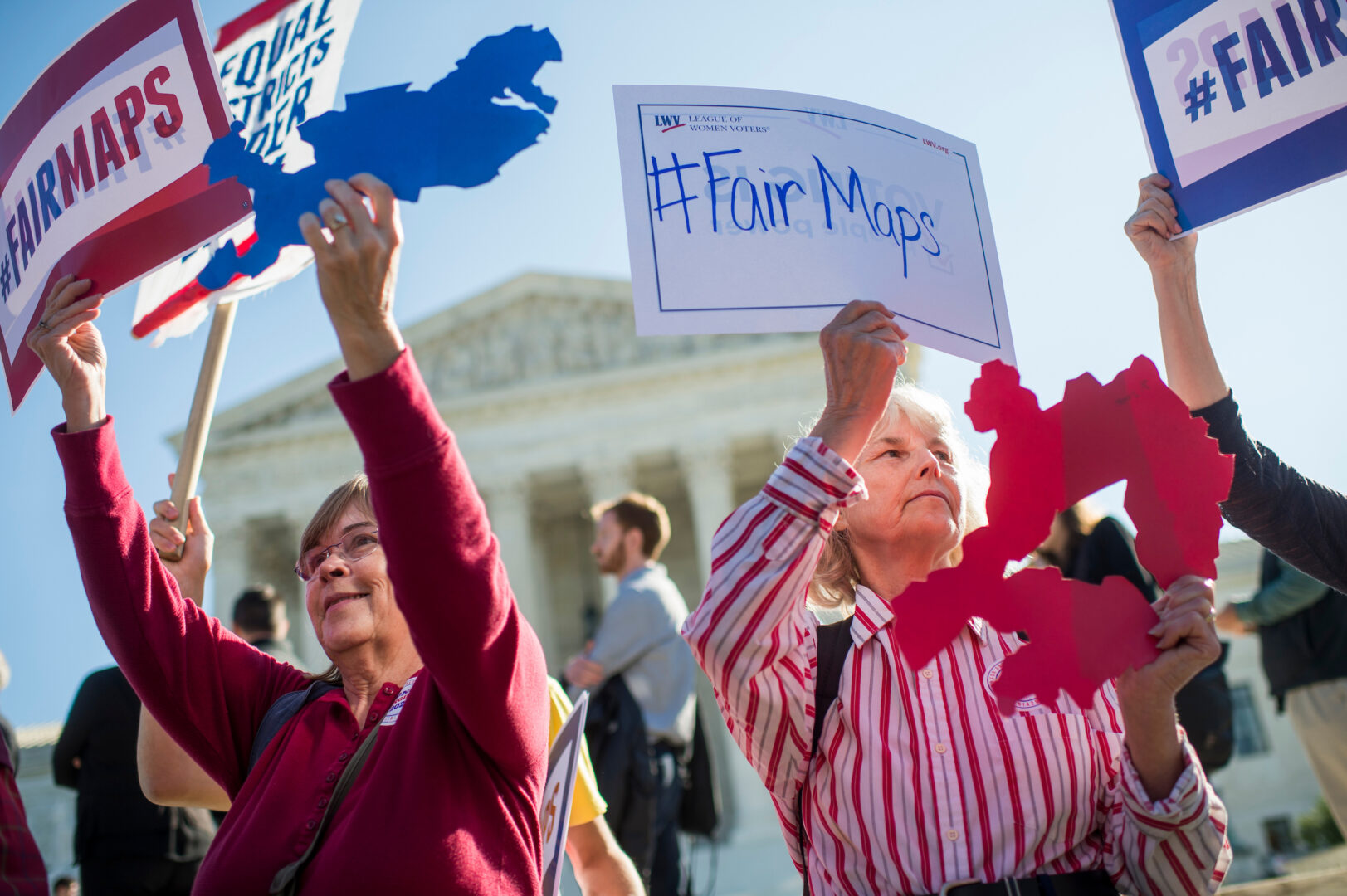 Concerns about gerrymandering aren’t new, but both parties have taken things to a new level with the help of technology and the courts, Winston writes. Above, protesters hold up signs as the Supreme Court hears a case in October 2017. 