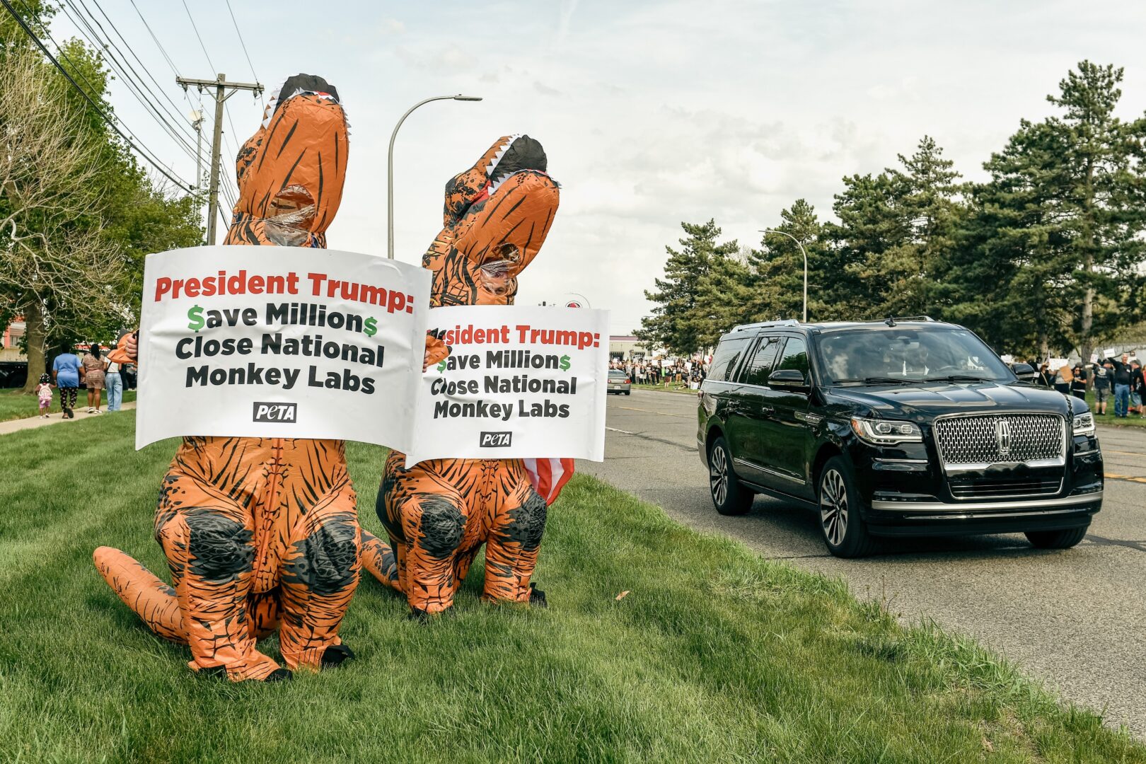 Members of PETA hold signs calling for animal testing to be shut down as cars pass by approximately 3,000 other protesters showing their displeasure for President Trump's policies outside of Macomb Community College in Warren, Mich., on April 29, 2025.