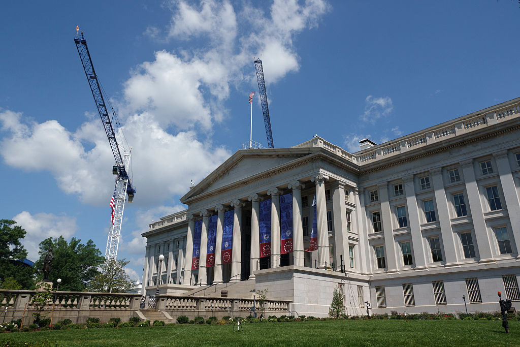 Cranes from the White House East Wing ballroom construction project are seen behind the Treasury Department building on June 7. (Kevin Carter/Getty Images)