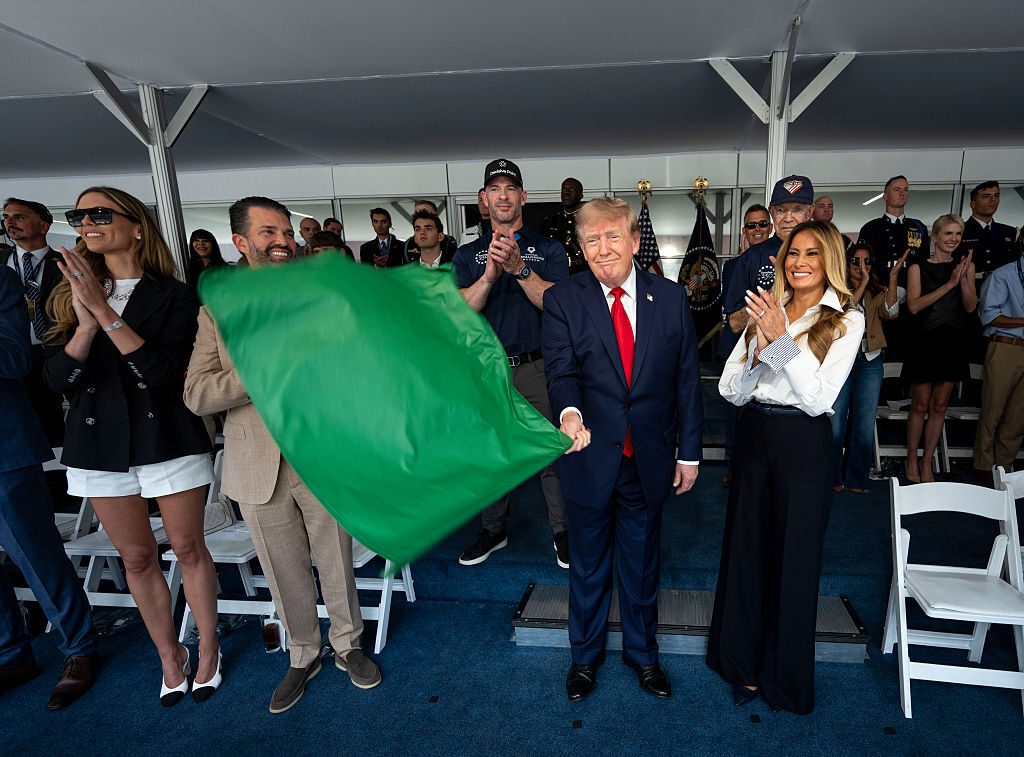 President Donald Trump waves the green flag to start the Freedom 250 Grand Prix in downtown Washington, D.C., on Sunday as first lady Melania Trump and Donald Trump Jr. look on. (Doug Mills/Getty Images)