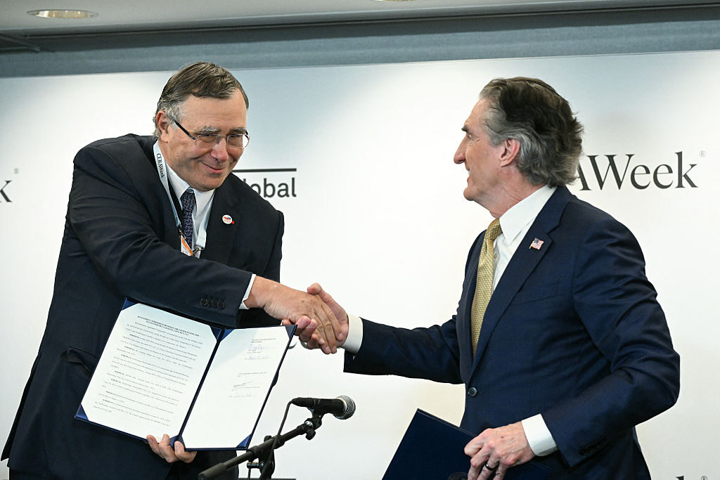 TotalEnergies CEO Patrick Pouyanne shakes hands with Burgum after signing an agreement to end the French company's U.S. offshore wind projects during the 2026 CERAWeek by S&P Global energy conference in Houston on March 23. (Ronaldo Schemidt/AFP via Getty Images)