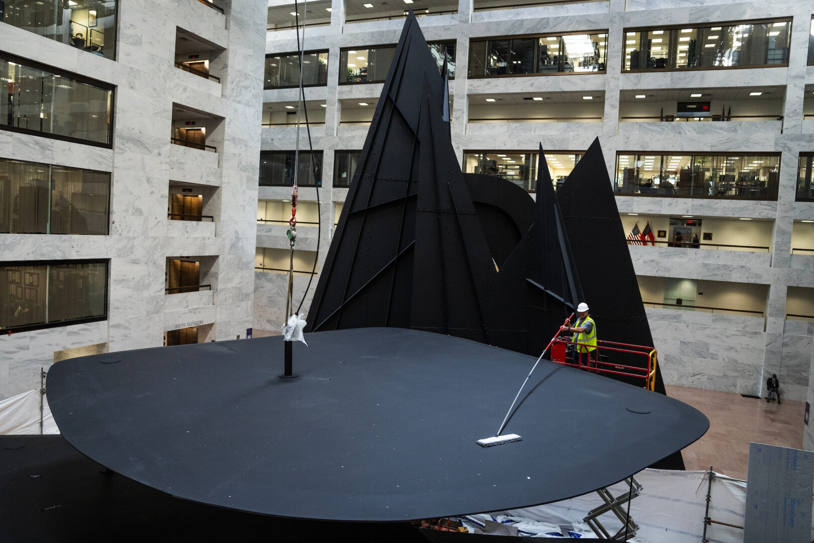 A worker sweeps part of the Mountains and Clouds sculpture on Friday ahead of its reinstallation. 