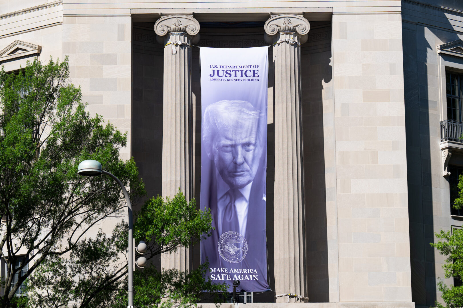 A banner featuring a photo of President Donald Trump hangs outside the Justice Department in Washington on June 15.